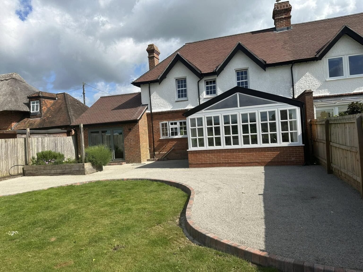Permeable resin-bound paving with decorative aggregates and willow screening in an environmentally-conscious Aldermaston property, sustainably installed by AJR Landscaping.