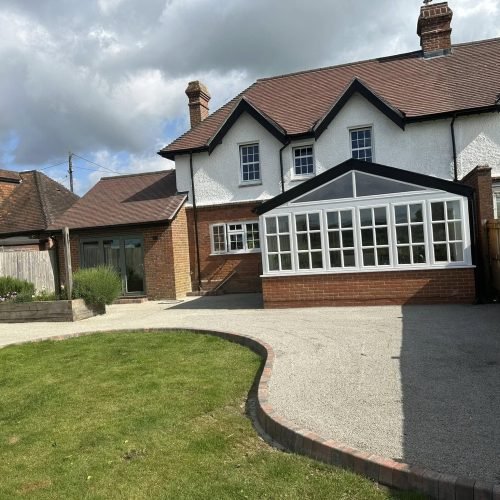 Permeable resin-bound paving with decorative aggregates and willow screening in an environmentally-conscious Aldermaston property, sustainably installed by AJR Landscaping.